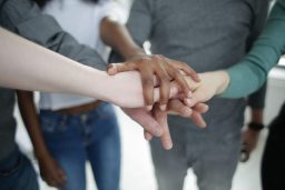 Mensen met verschillende huidskleuren leggen handen bij elkaar